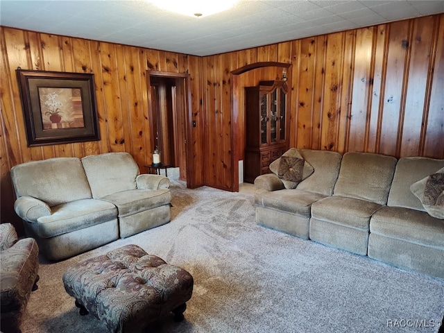 carpeted living room featuring wood walls