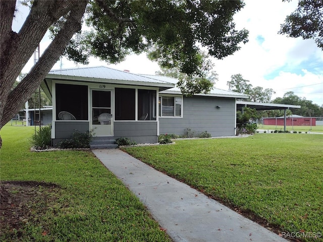 view of front facade featuring a sunroom, a front lawn, and a carport