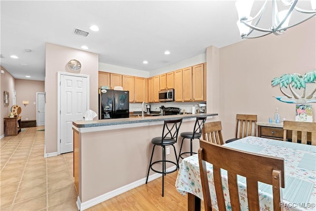 kitchen with black appliances, light brown cabinets, a notable chandelier, hanging light fixtures, and light tile patterned flooring