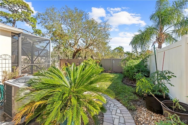 view of yard featuring central AC unit and glass enclosure