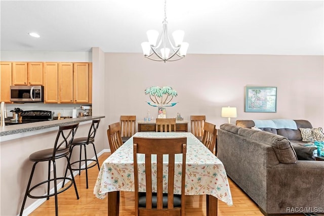 dining space with an inviting chandelier and light hardwood / wood-style flooring