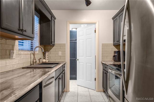 kitchen featuring tasteful backsplash, dark brown cabinetry, stainless steel appliances, sink, and light tile patterned floors