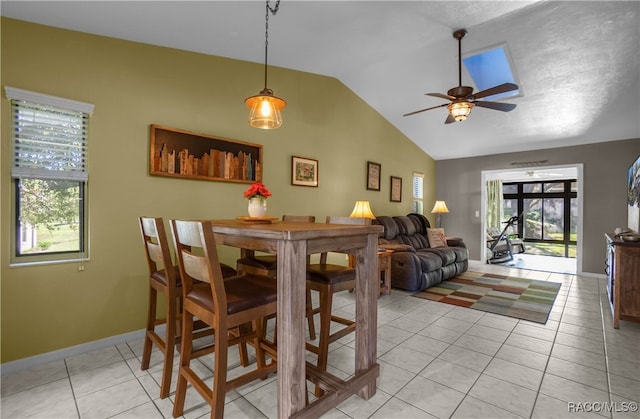 tiled dining space with ceiling fan and vaulted ceiling