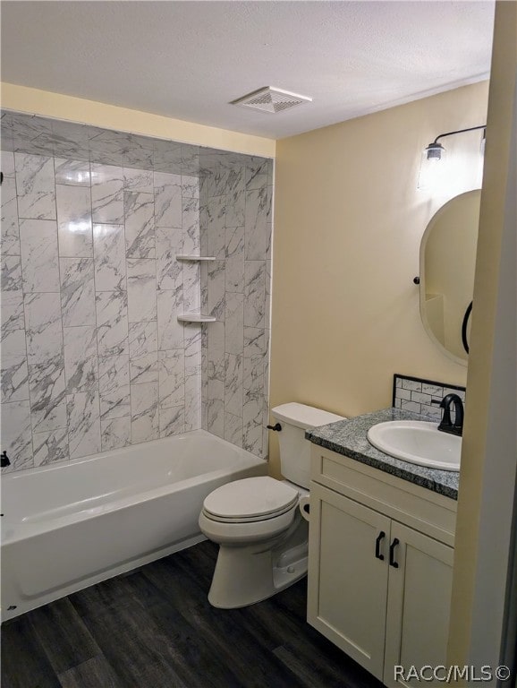 full bathroom with hardwood / wood-style floors, vanity, toilet, and tiled shower / bath