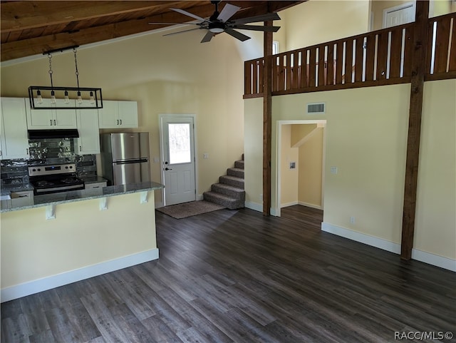 kitchen featuring beam ceiling, dark stone counters, white cabinets, and stainless steel appliances