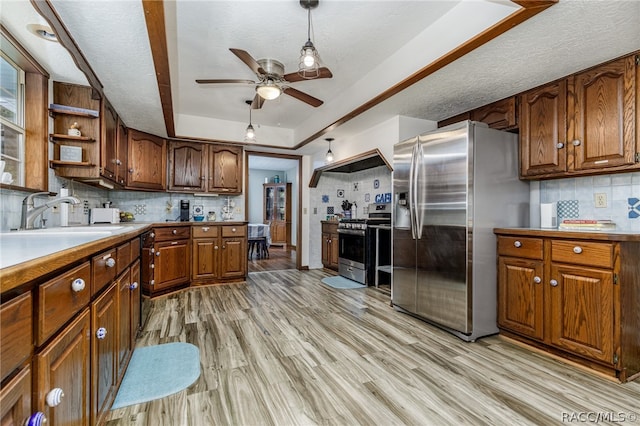 kitchen with appliances with stainless steel finishes, backsplash, light hardwood / wood-style floors, and a raised ceiling