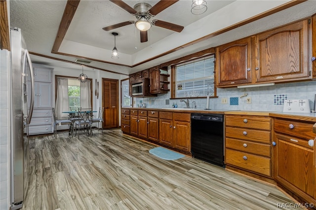 kitchen with backsplash, light hardwood / wood-style floors, decorative light fixtures, a tray ceiling, and appliances with stainless steel finishes