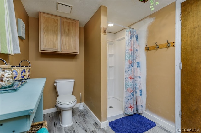 bathroom with a shower with curtain, toilet, and hardwood / wood-style floors