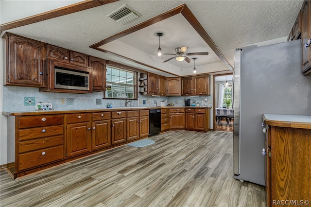 kitchen featuring ceiling fan, light hardwood / wood-style floors, a textured ceiling, a tray ceiling, and appliances with stainless steel finishes