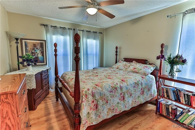 bedroom with light wood finished floors, ceiling fan, and a textured ceiling