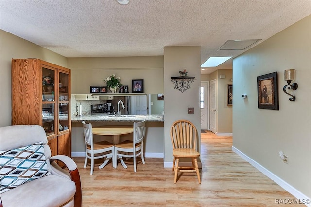 interior space with baseboards, a textured ceiling, and light wood-style floors