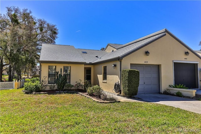 view of front of property with stucco siding, an attached garage, fence, and a front yard