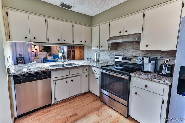 kitchen with visible vents, stainless steel appliances, a textured ceiling, under cabinet range hood, and a sink