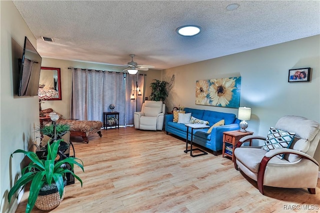 living area featuring ceiling fan, a textured ceiling, visible vents, and wood finished floors