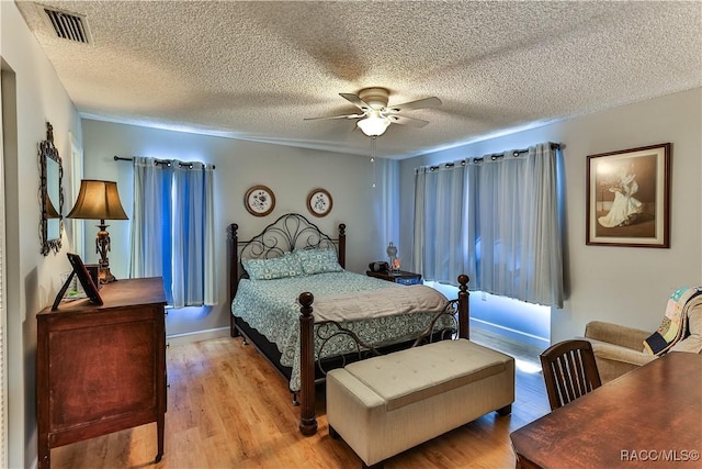 bedroom with ceiling fan, a textured ceiling, light wood-type flooring, and visible vents