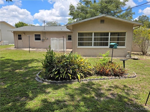 215 S Jefferson St, Beverly Hills, FL 34465 - rear view of property with stucco siding and a lawn
