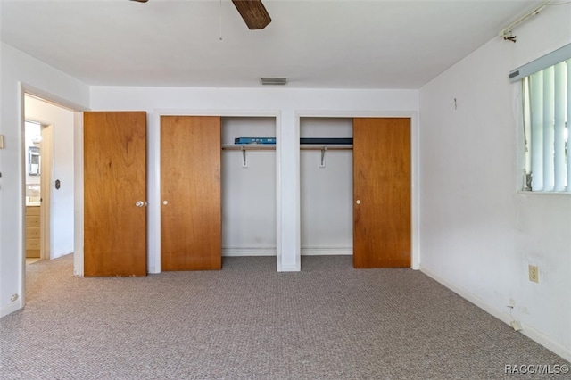 unfurnished bedroom with multiple closets, ceiling fan, and carpet floors