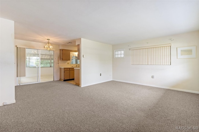 unfurnished living room with plenty of natural light, light colored carpet, and a chandelier