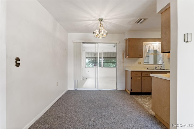 kitchen with pendant lighting, sink, tasteful backsplash, a notable chandelier, and light colored carpet