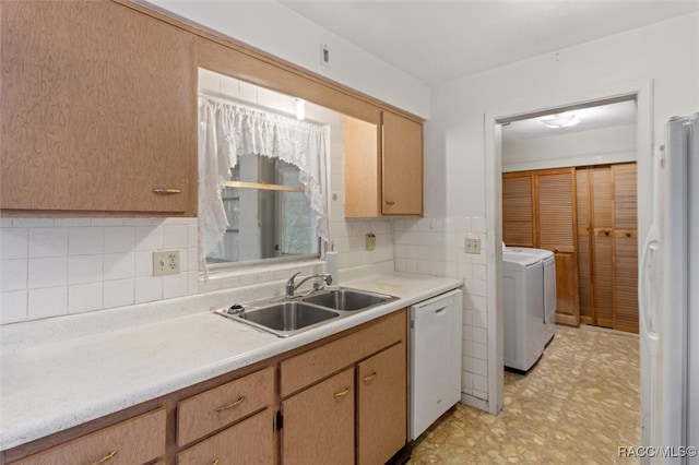 kitchen with backsplash, sink, washer and dryer, and white appliances