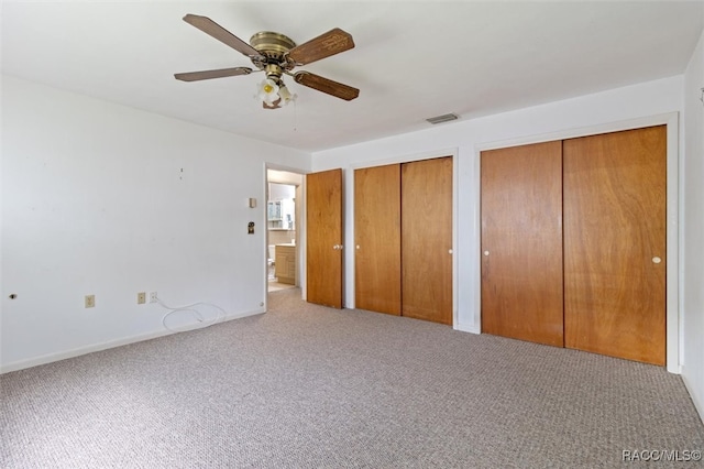 unfurnished bedroom featuring light colored carpet, ceiling fan, and multiple closets