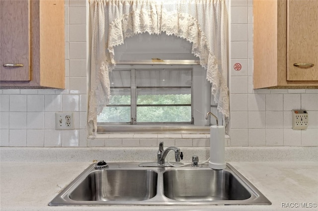 kitchen featuring backsplash, light stone counters, and sink