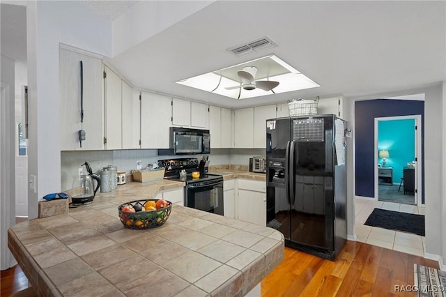 483 N Turkey Pine Loop, Lecanto, FL 34461 - kitchen featuring tile counters, black appliances, light wood-style floors, a peninsula, and visible vents