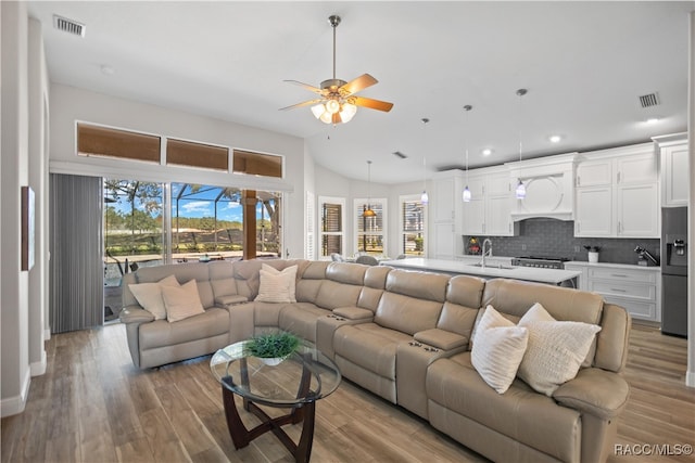 living room with sink, a wealth of natural light, ceiling fan, and light hardwood / wood-style flooring