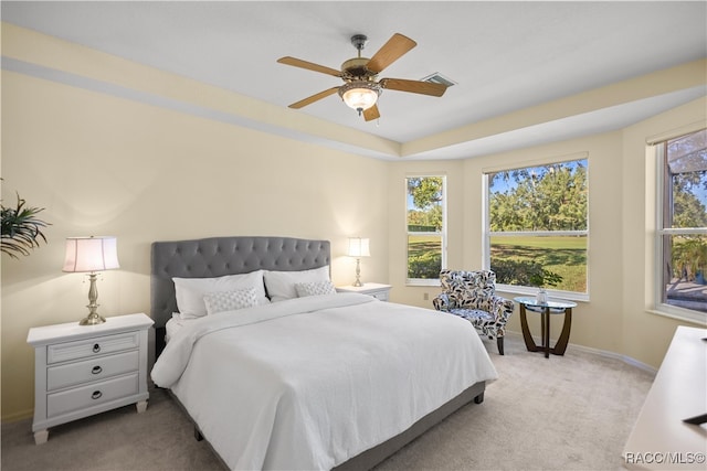 carpeted bedroom featuring multiple windows and ceiling fan