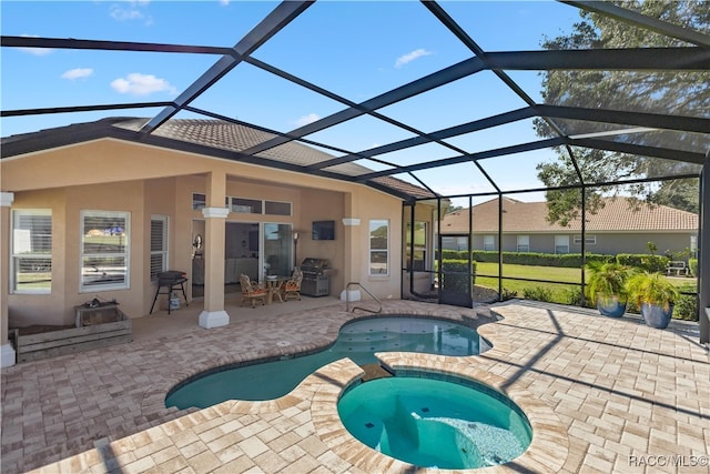 view of pool featuring glass enclosure, a pool with connected hot tub, and a patio