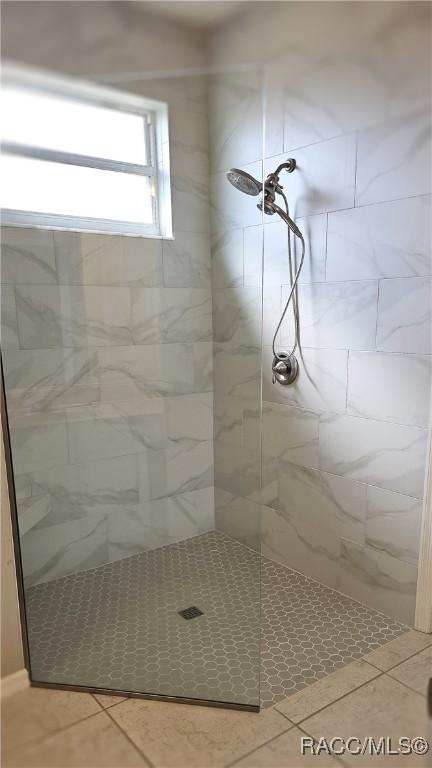 bathroom featuring tile patterned flooring and tiled shower