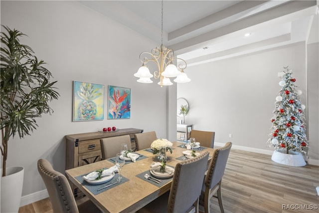 dining area featuring an inviting chandelier, baseboards, a tray ceiling, and wood finished floors