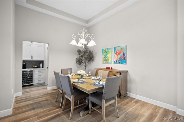 dining area with an inviting chandelier, beverage cooler, and light hardwood / wood-style floors