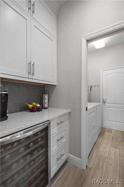 bar featuring white cabinetry, beverage cooler, separate washer and dryer, and light hardwood / wood-style flooring