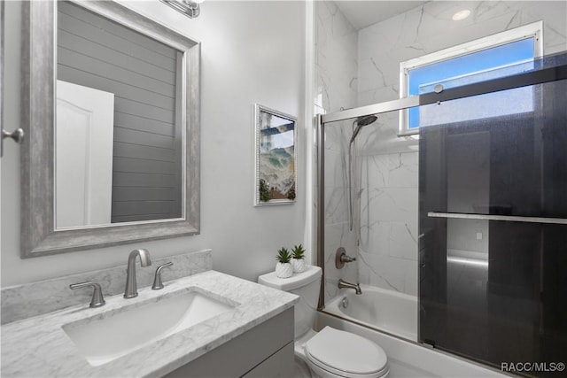 full bathroom featuring toilet, vanity, and bath / shower combo with glass door