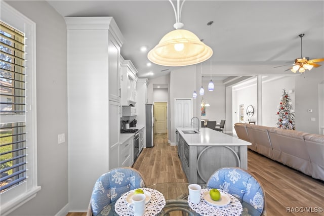 kitchen featuring light countertops, appliances with stainless steel finishes, open floor plan, a sink, and wood finished floors