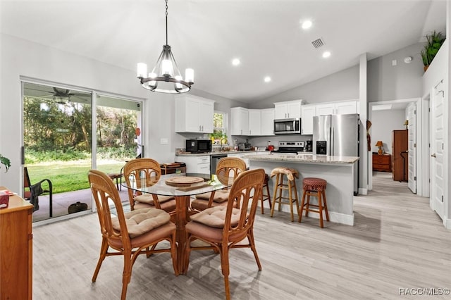 dining area with ceiling fan with notable chandelier, light hardwood / wood-style floors, and high vaulted ceiling