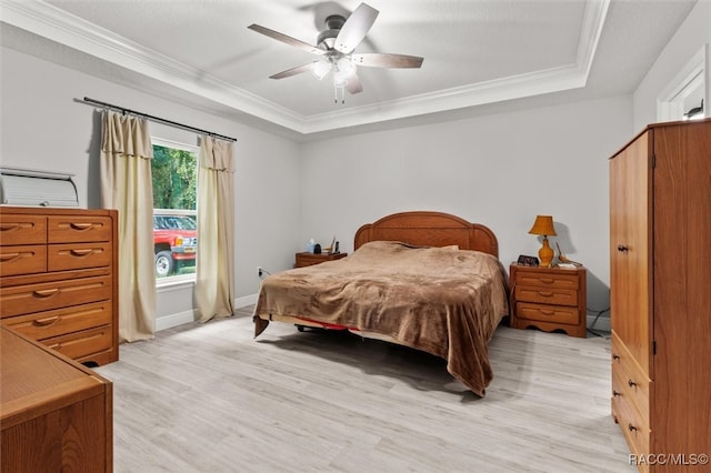 bedroom featuring a raised ceiling, light hardwood / wood-style flooring, ceiling fan, and crown molding