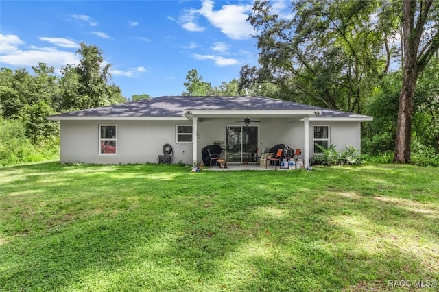 rear view of property featuring a lawn, ceiling fan, and a patio