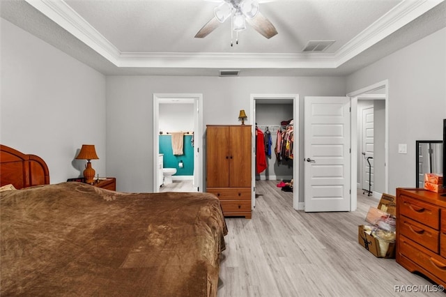 bedroom with a walk in closet, ceiling fan, crown molding, connected bathroom, and a closet