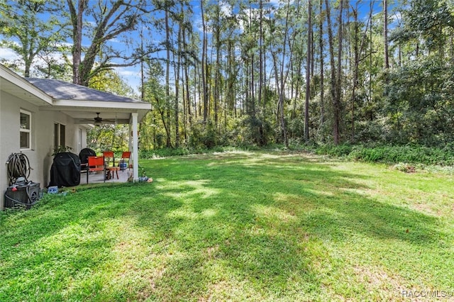 view of yard featuring ceiling fan and a patio