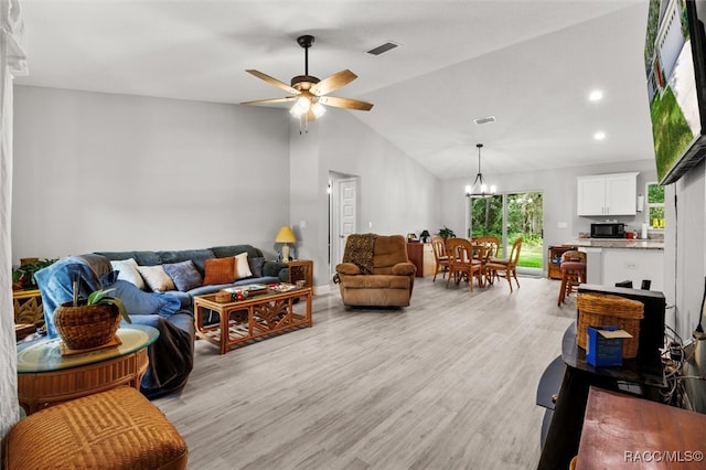 living room featuring ceiling fan with notable chandelier, light wood-type flooring, and vaulted ceiling