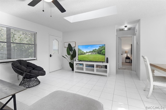 living room featuring ceiling fan, light tile patterned floors, and a textured ceiling