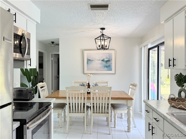 dining space featuring ceiling fan with notable chandelier, light tile patterned floors, and a textured ceiling