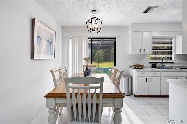 dining area featuring a chandelier, light tile patterned floors, a healthy amount of sunlight, and sink