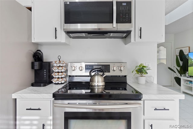 kitchen featuring a textured ceiling, white cabinets, stainless steel appliances, and light tile patterned floors