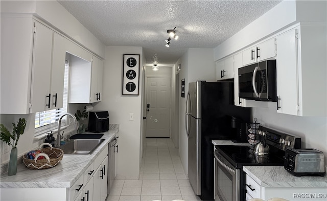 kitchen with white cabinets, sink, stainless steel appliances, and a textured ceiling