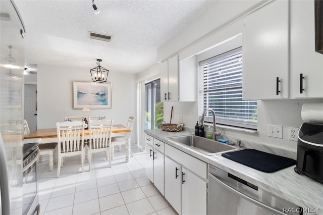 kitchen with white cabinetry, sink, pendant lighting, and a notable chandelier