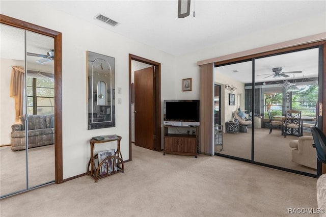 carpeted living room with visible vents, a ceiling fan, and a wealth of natural light