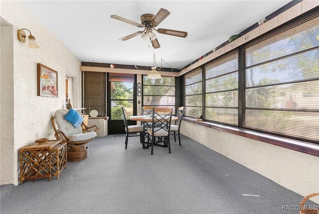 sunroom / solarium featuring a textured wall and ceiling fan